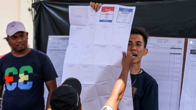Anggota Kelompok Penyelenggara Pemungutan Suara (KPPS) menunjukkan surat suara kepada para saksi saat dilakukan perhitungan lanjutan di TPS bersebelahan dengan Pos Lanal Pusong di Desa Pusong Baru, Lhokseumawe, Aceh